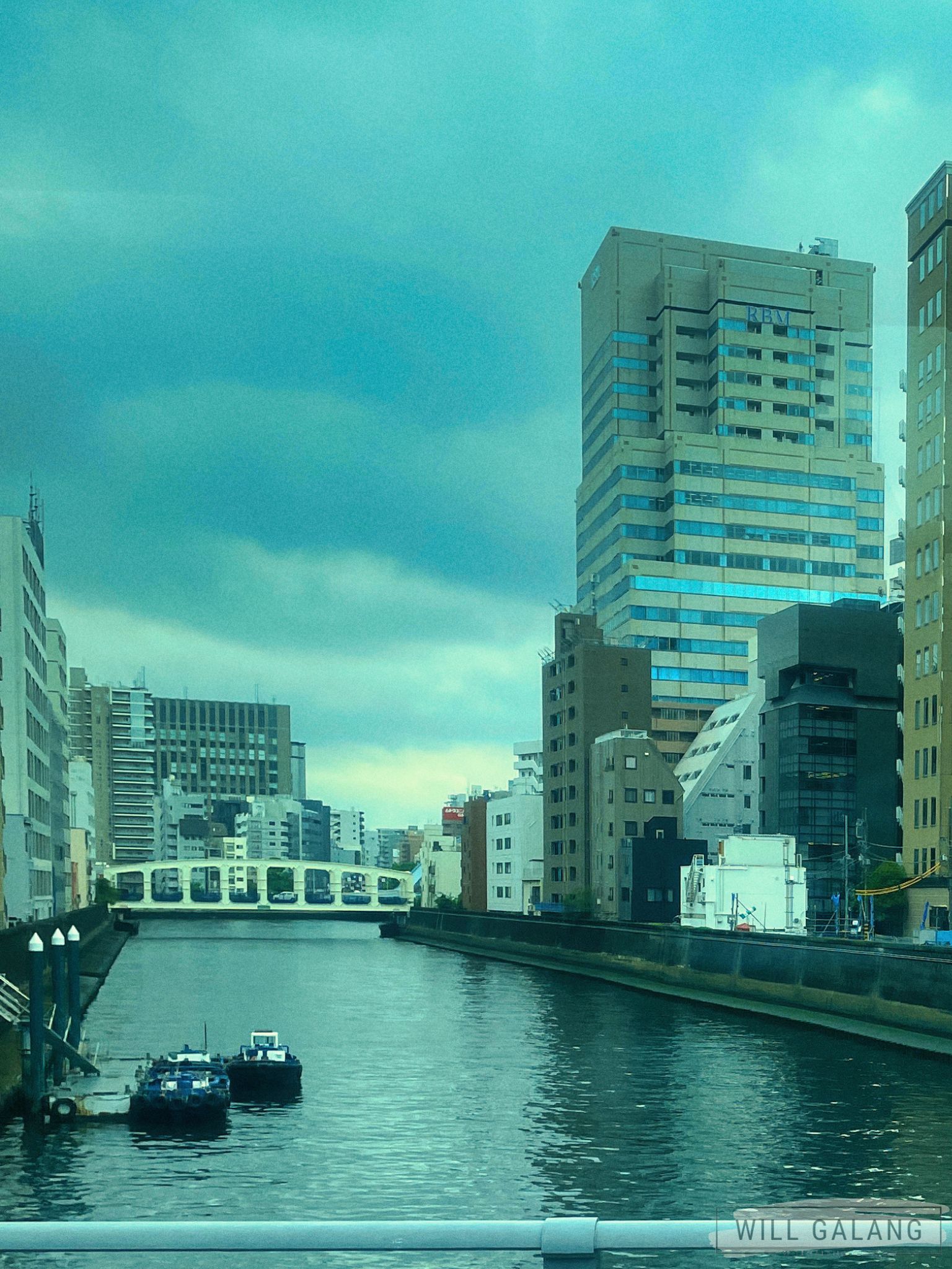 The Kayabachō Tower rises like a modern lighthouse, keeping watch over Shinkawa’s Sumida river's calmness.